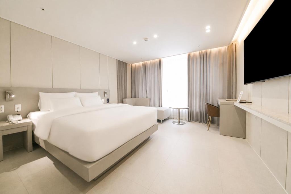 a bedroom with a large white bed and a television at 제니스 호텔 in Jecheon