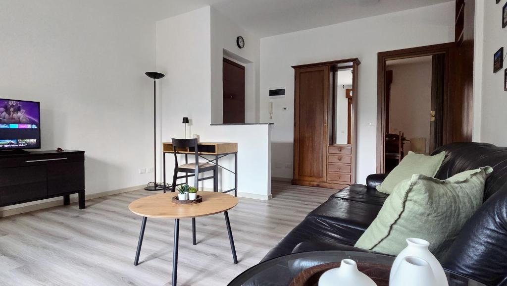 a living room with a black leather couch and a table at MAGIA - Tra Laghi e Montagne in Gravellona Toce
