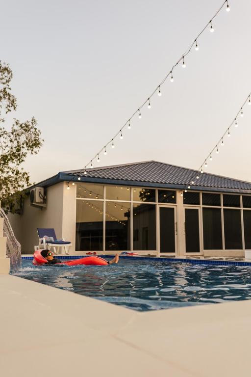 eine Person, die im Swimmingpool eines Hauses liegt in der Unterkunft ALSARA HiDEAWAY in Qūr