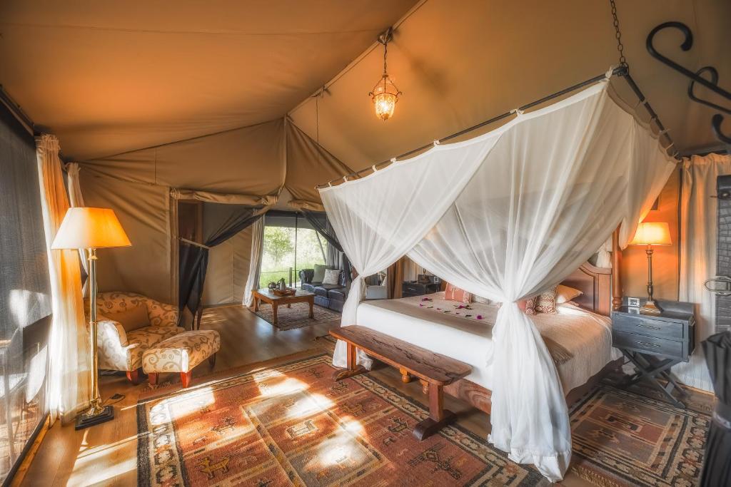 a bedroom with a canopy bed in a tent at Elewana Sand River Mara in Talek