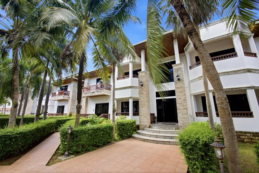 a building with palm trees in front of it at Rawai Grand House -SHA Plus in Rawai Beach