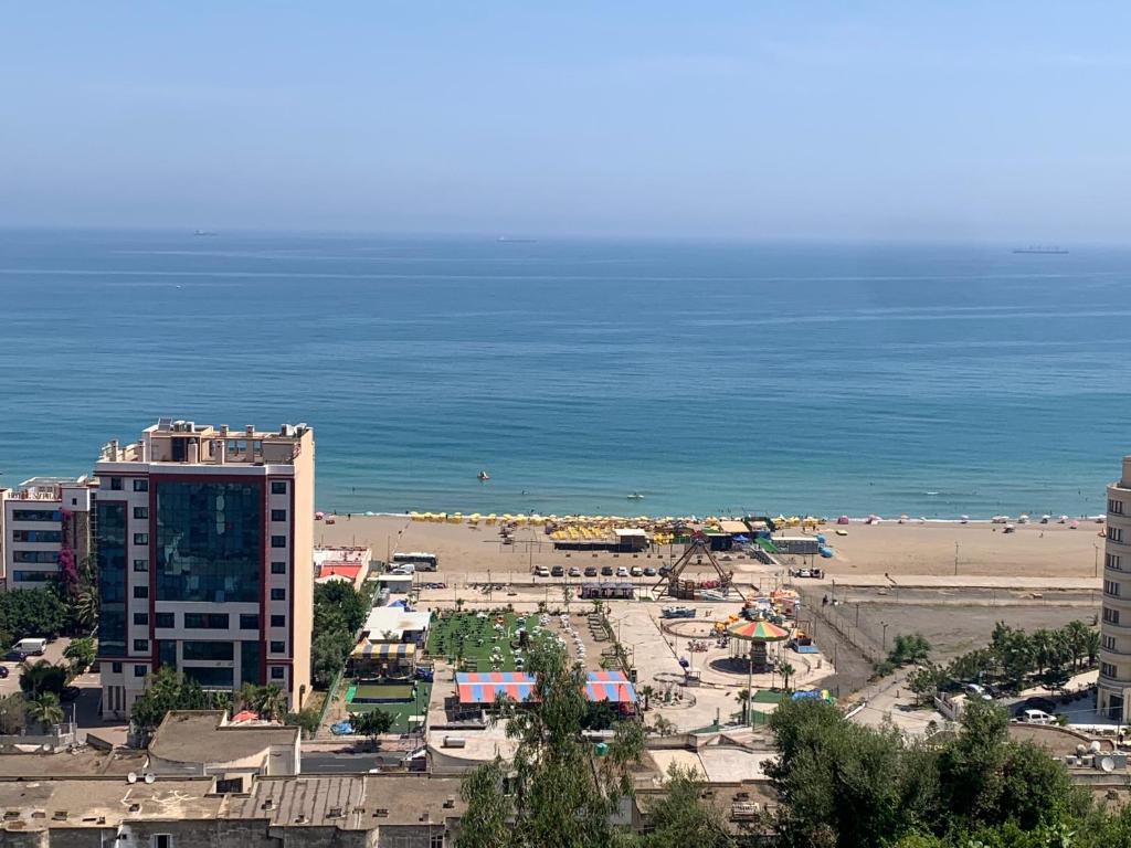 a view of a beach with a building and the ocean at Chez NAIM in Tichi