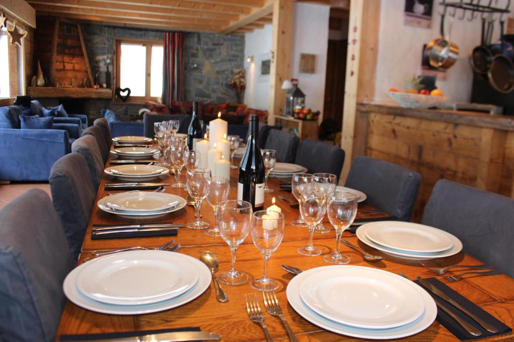 a long wooden table with plates and wine glasses at Chalet Le Plan des Rochers in Morzine