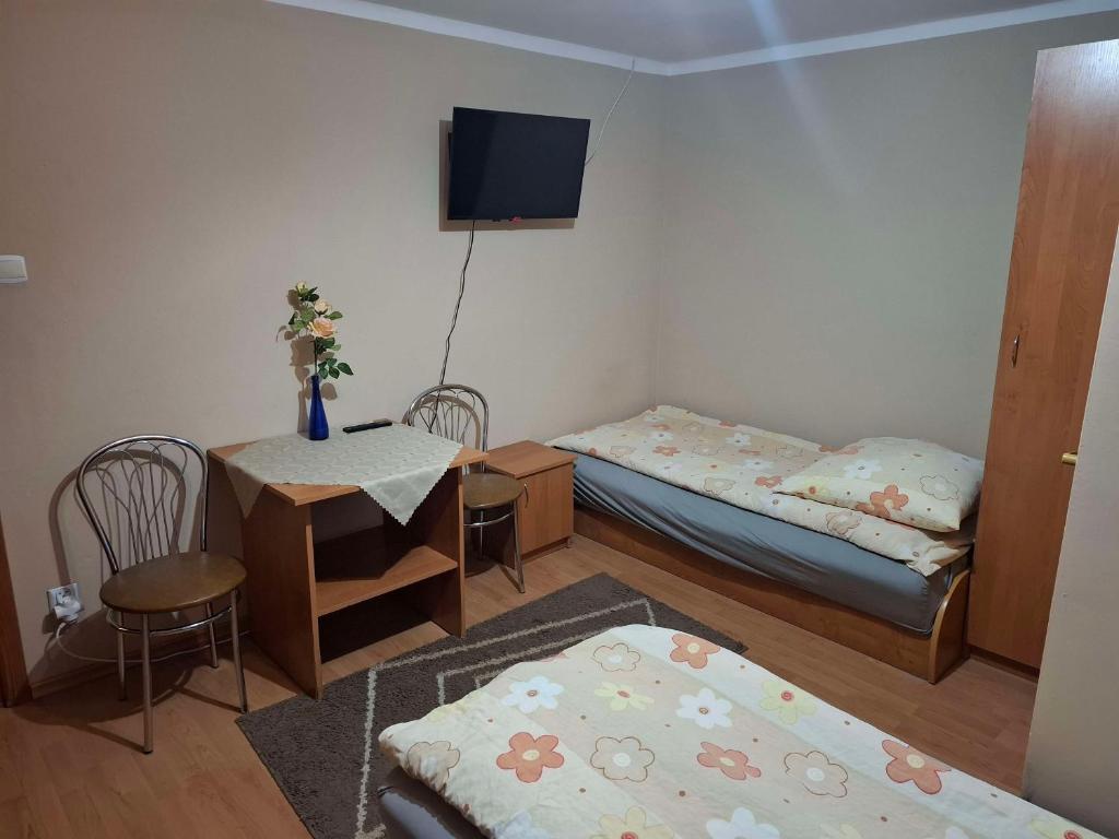 a room with two beds and a table and a tv at Agroturystyka nad rzeczką in Szymany