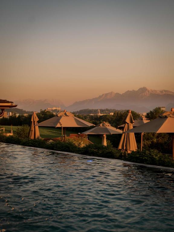 Blick auf einen Pool mit Sonnenschirmen und Wasser in der Unterkunft Genussdorf Gmachl - Hotel & Spa in Bergheim