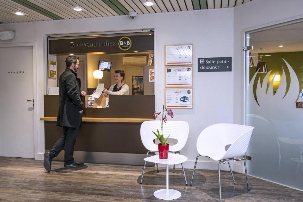 a man is standing in front of a cash register at B&B HOTEL La Rochelle Centre in La Rochelle