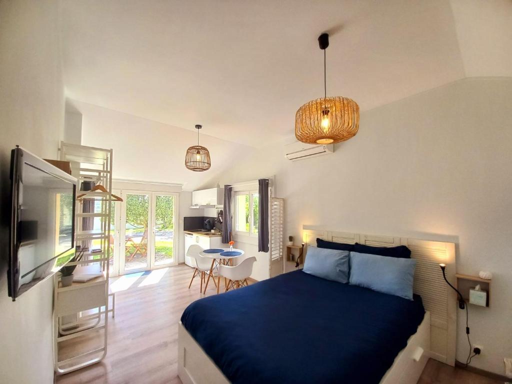 a bedroom with a blue bed and a dining room at Studio cosy avec terrasse privée - arrivée autonome in Rouffiac-Tolosan