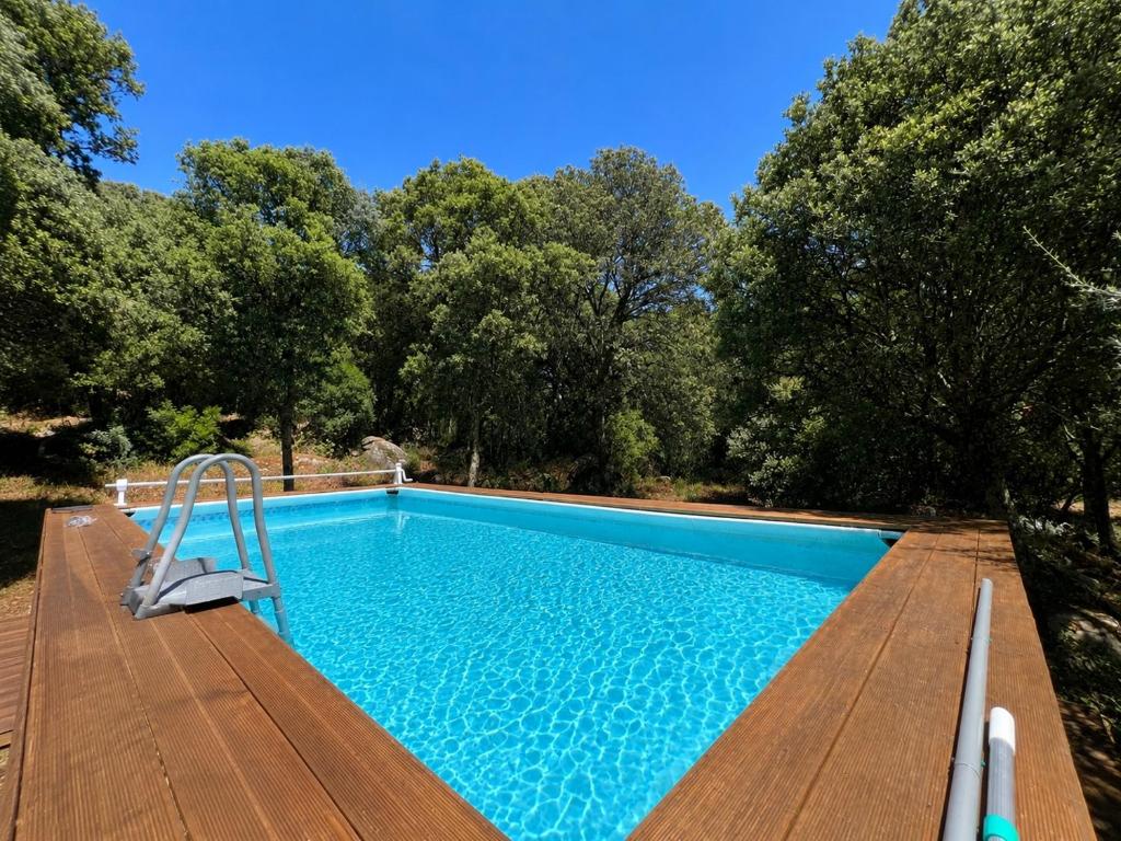 a swimming pool on a wooden deck with trees at Casa La Liccia in Calangianus