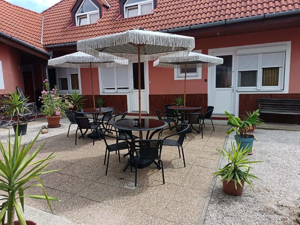 an outdoor patio with tables and chairs with umbrellas at Basti Apartman in Gyenesdiás