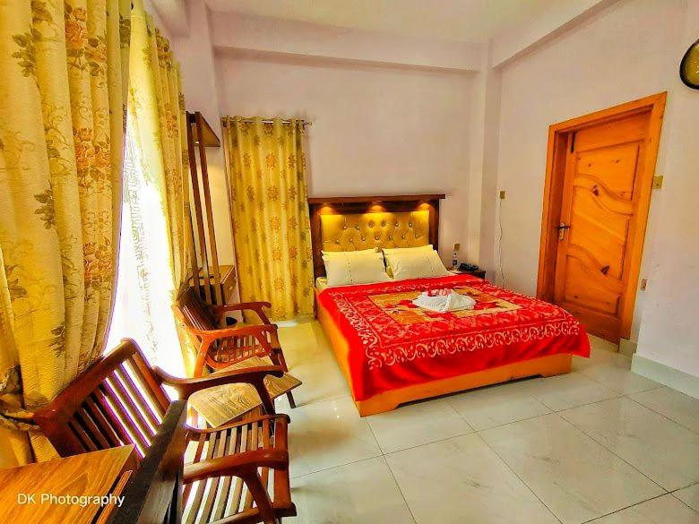 a bedroom with a bed with a red bedspread at Grand palace hotel kumrat in Tāl