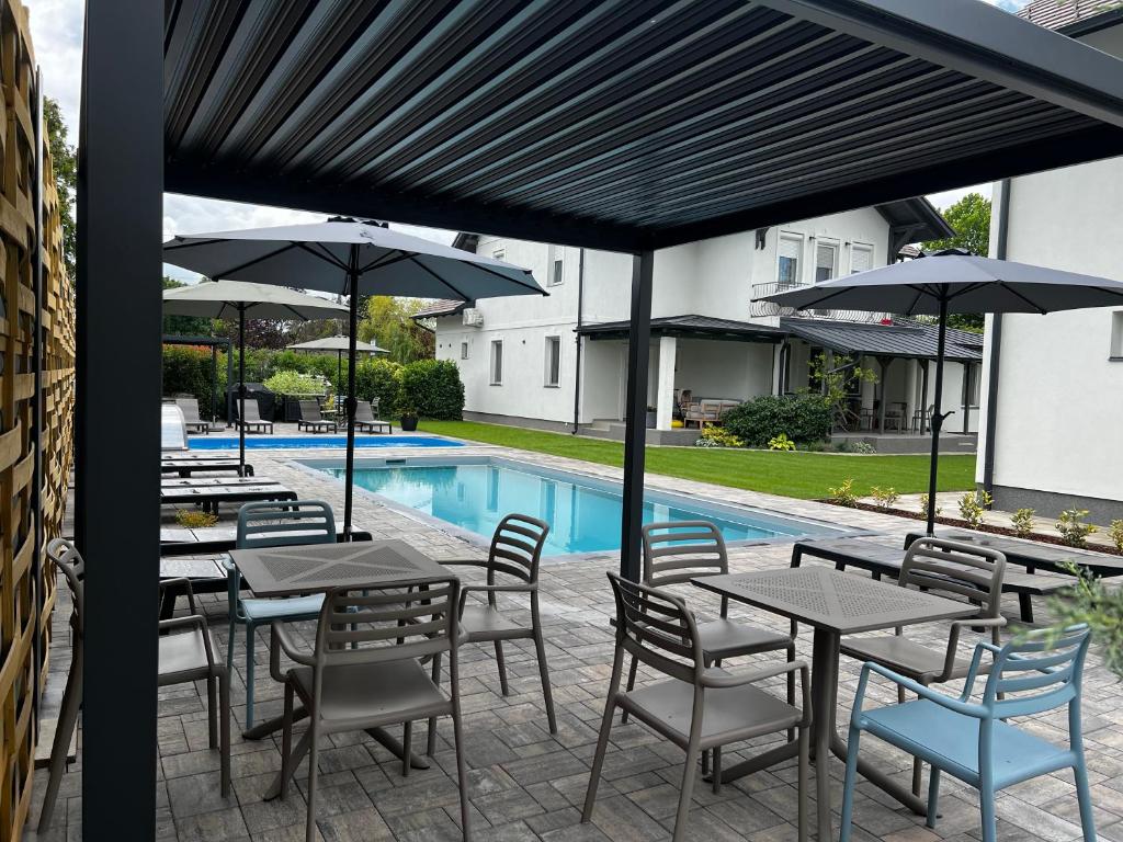 a patio with tables and umbrellas next to a pool at Best Apartman Lelle 2 in Balatonlelle