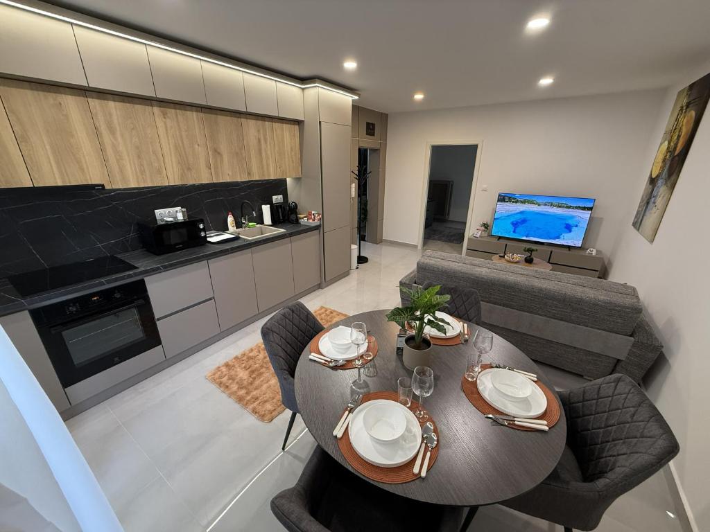 a kitchen and a living room with a table and chairs at ViA Lux Apartman in Pécs