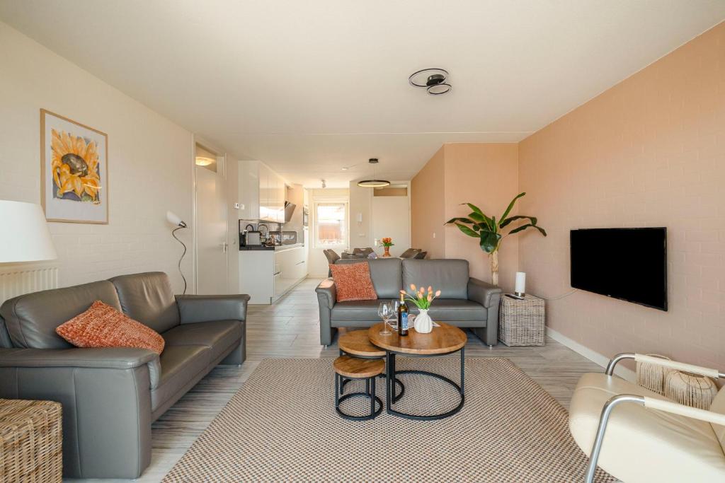 a living room with a couch and a tv at Dorpsplein 42 in Callantsoog