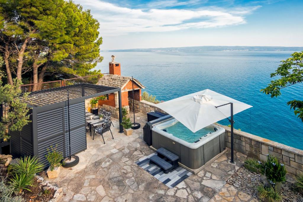 an outdoor hot tub with an umbrella next to the water at SUPER HORIZONT- Sea View Apartments with private Jacuzzi time & Free Parking in Split