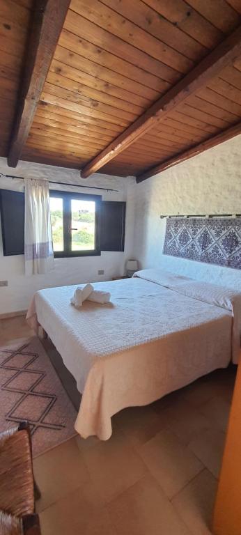 a bedroom with a large bed with a wooden ceiling at Sorres Agriturismo in Tanaunella
