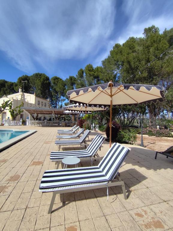 a row of lounge chairs with umbrellas next to a pool at Casa de La Campana in Cieza