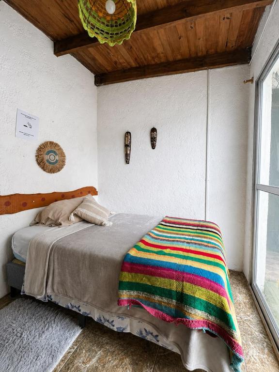 a bedroom with a bed with a colorful blanket on it at Alojamiento EYO en Chuy con Baño Privado y Aire Acondicionado in Chuy