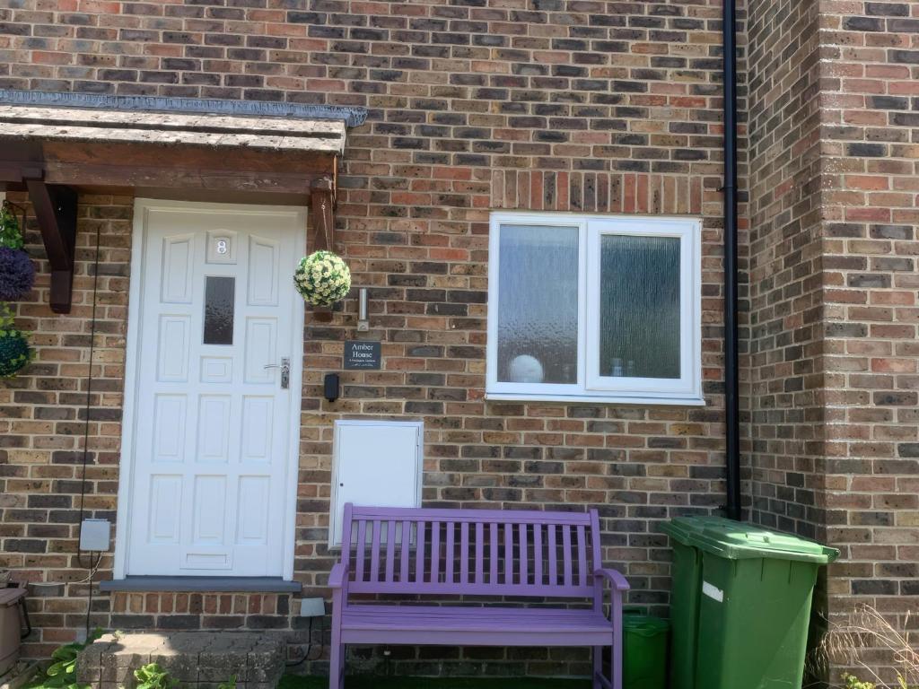 a purple bench sitting in front of a brick house at Amber House in Dorchester