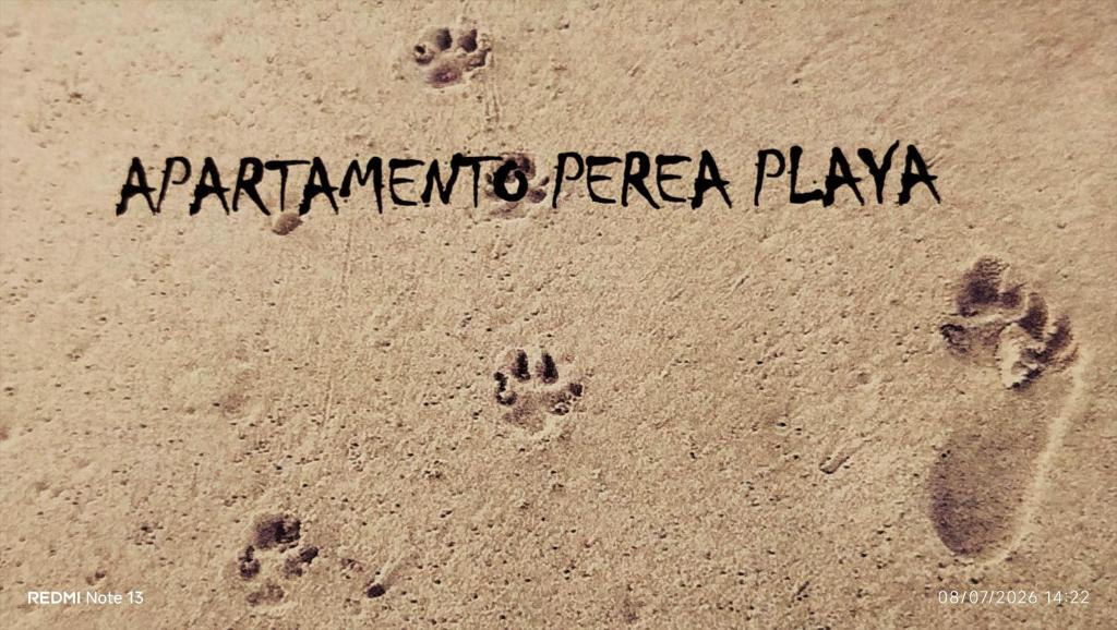 a sign on the sand with footprints in the sand at Apartamento Perea playa in Tavernes de Valldigna