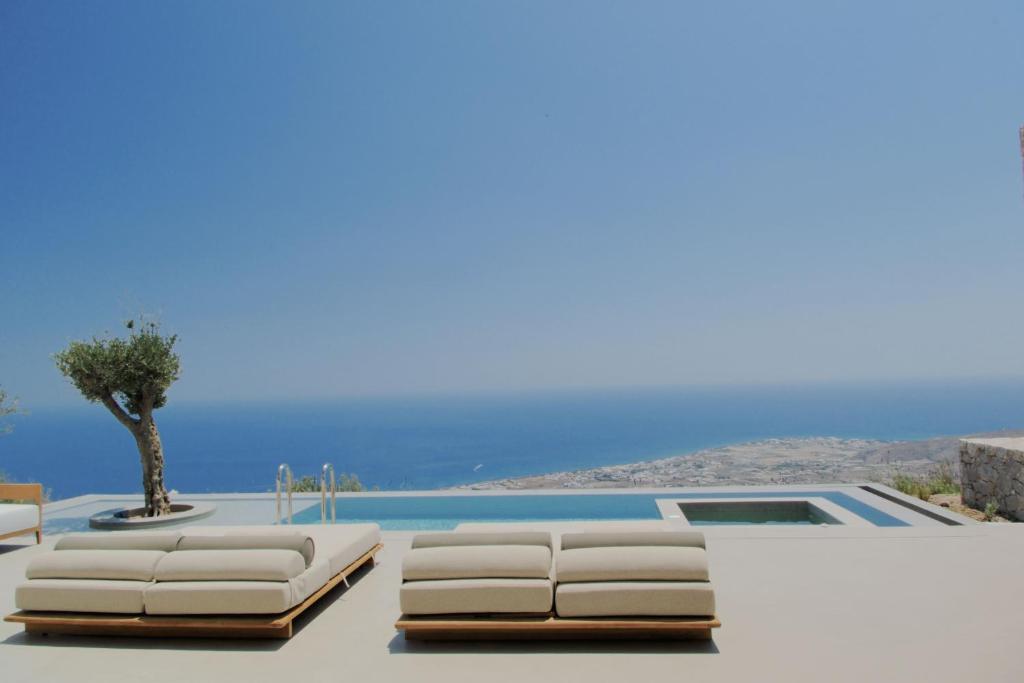 a villa with a pool and white furniture at VOUNO Santorini Private Villas in Pyrgos