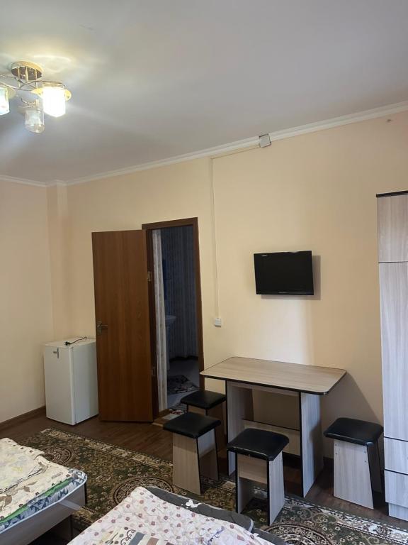a room with a table and chairs and a television at Достук in Bosteri