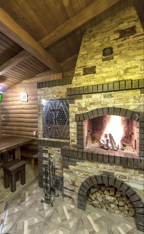 a stone fireplace in a room with a wooden ceiling at Над Річкою in Yaremche