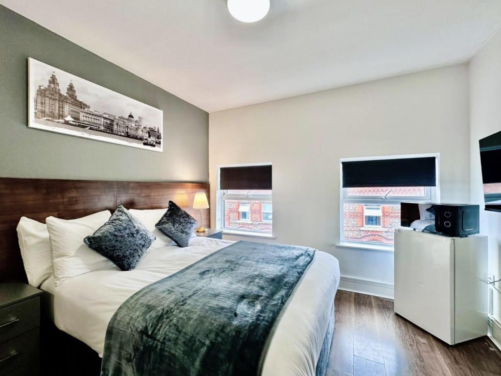 a bedroom with a large bed and two windows at Trivelles Liverpool in Liverpool