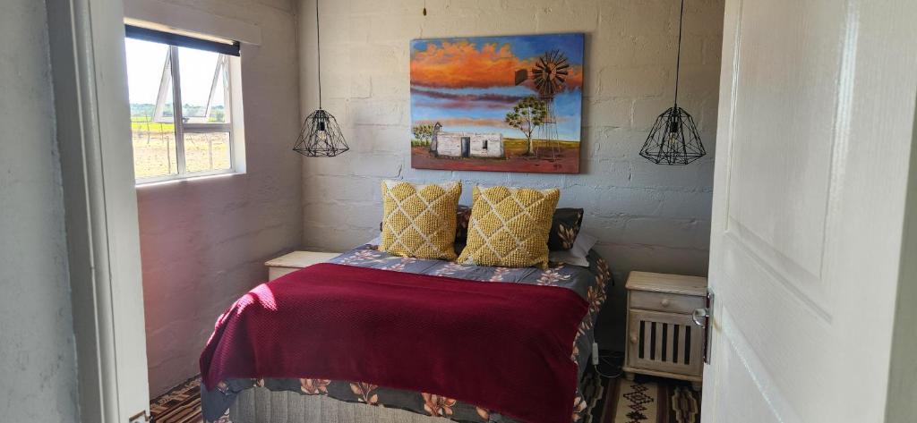 a small bedroom with a bed with a red blanket at Volgenoeg Self Catering Family Unit in Oudtshoorn