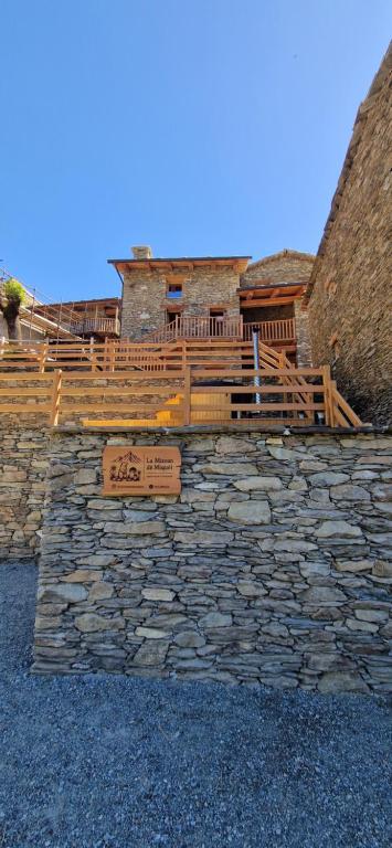 a building with a stone wall with a wooden deck at La Mizoun dë Miquél in Ostana