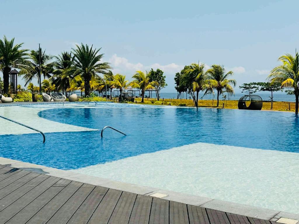 a large swimming pool with palm trees and the ocean at Endless Summer Seafront - 1BR Beach Resort Condo in San Juan