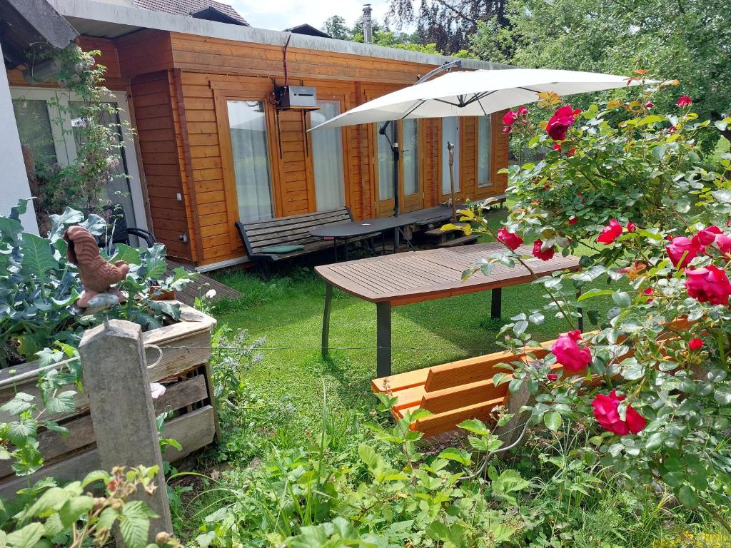 a picnic table with an umbrella in a yard with roses at Haus im Garten in Grebenau