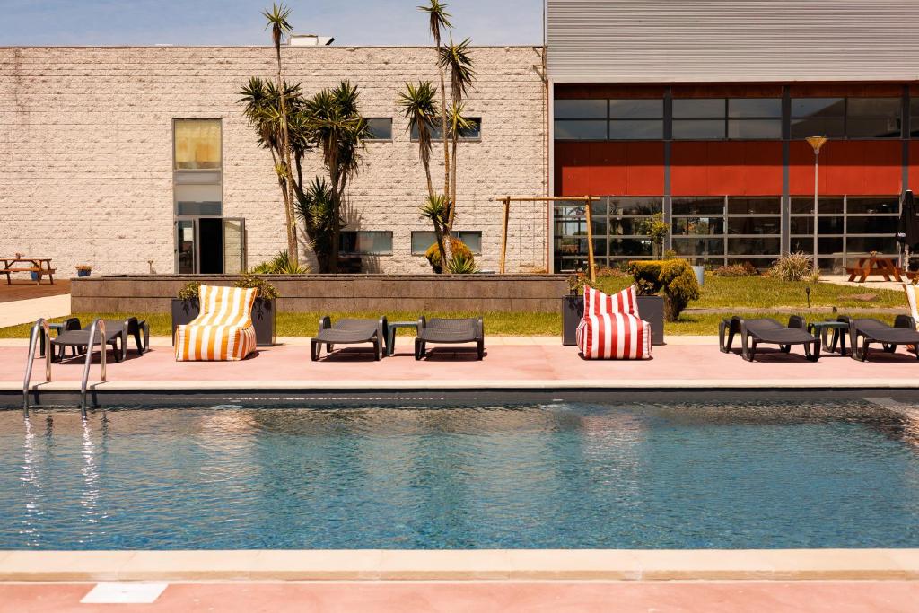 a pool with benches and chairs next to a building at Hotel Colombo in Vila do Porto