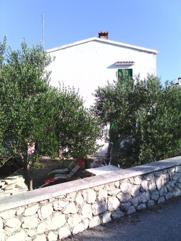 a stone retaining wall in front of a white building at Apartman Juliana in Stara Novalja