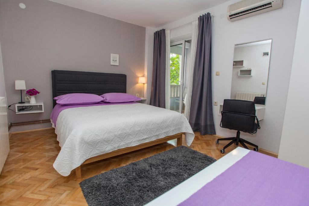 ein Schlafzimmer mit einem Bett mit lila Kissen und einem Stuhl in der Unterkunft Villa Makarana Apartments in Makarska