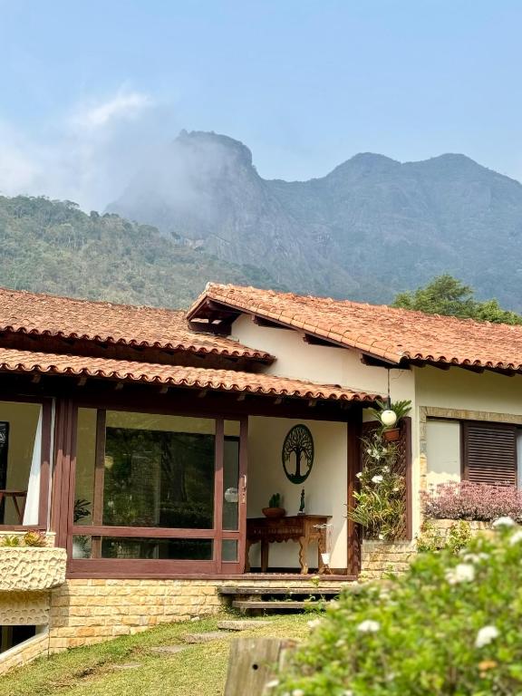 a house with a table and mountains in the background at Alto Paraiso in Teresópolis