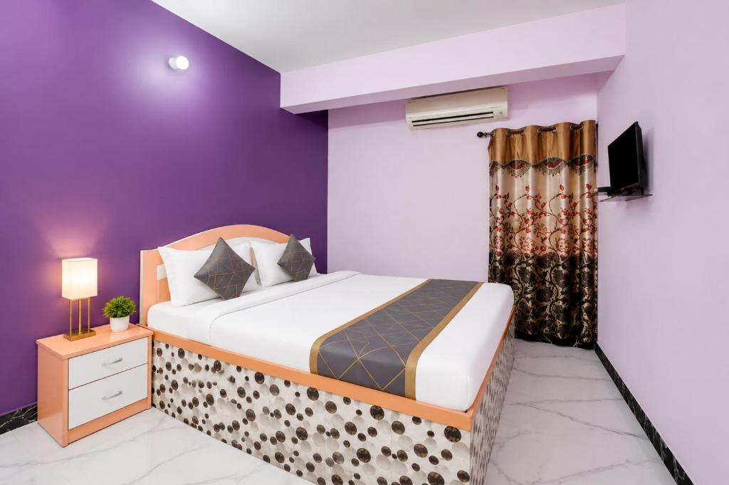 a bedroom with a bed and a purple wall at Triotel Inn in Dhanbād