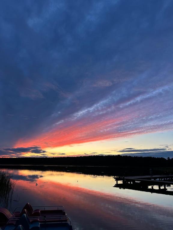 a sunset over a lake with boats in the water at Noclegi nad jeziorem in Wiartel Mały