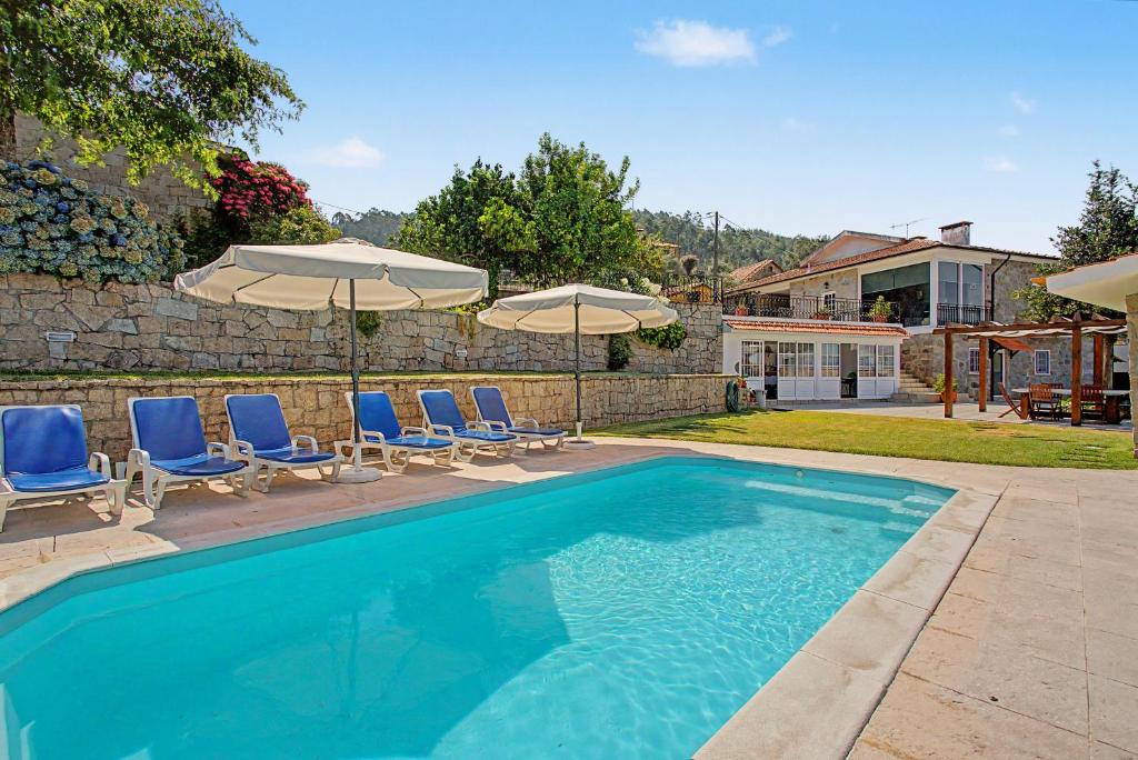 a swimming pool with chairs and umbrellas at Casa Da Redouça in Cedrim