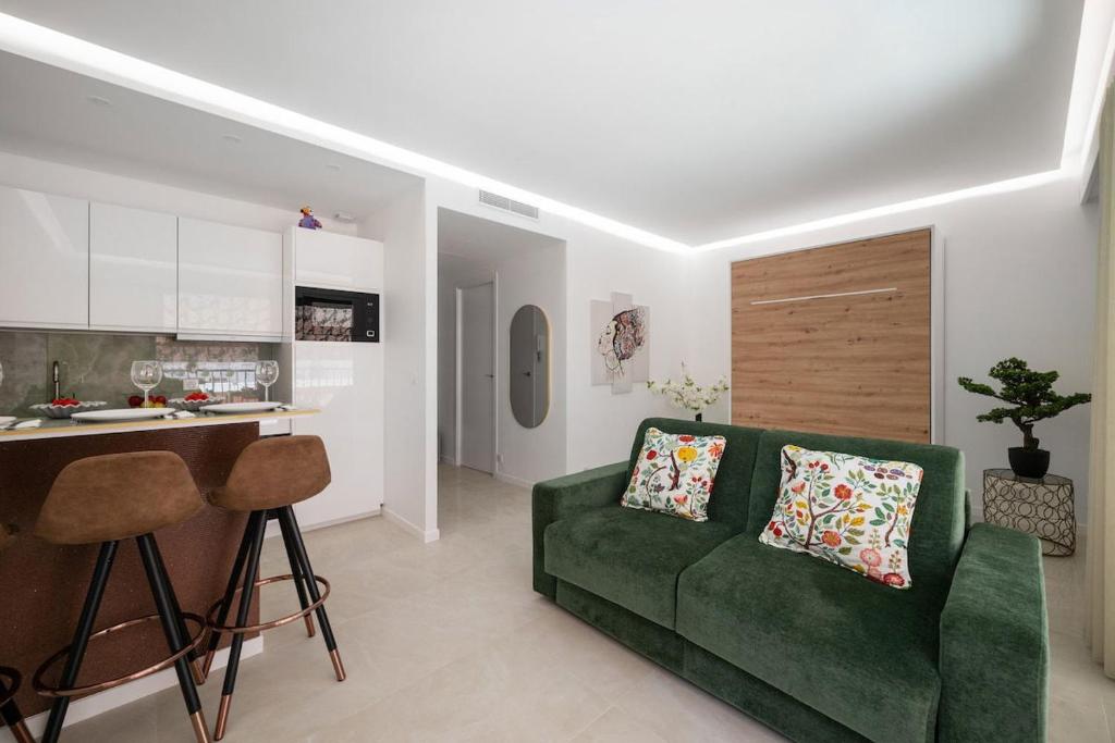 a living room with a green couch and a kitchen at LAMAZONICO - Proche Centre - Terrasse Clim Plage in Menton