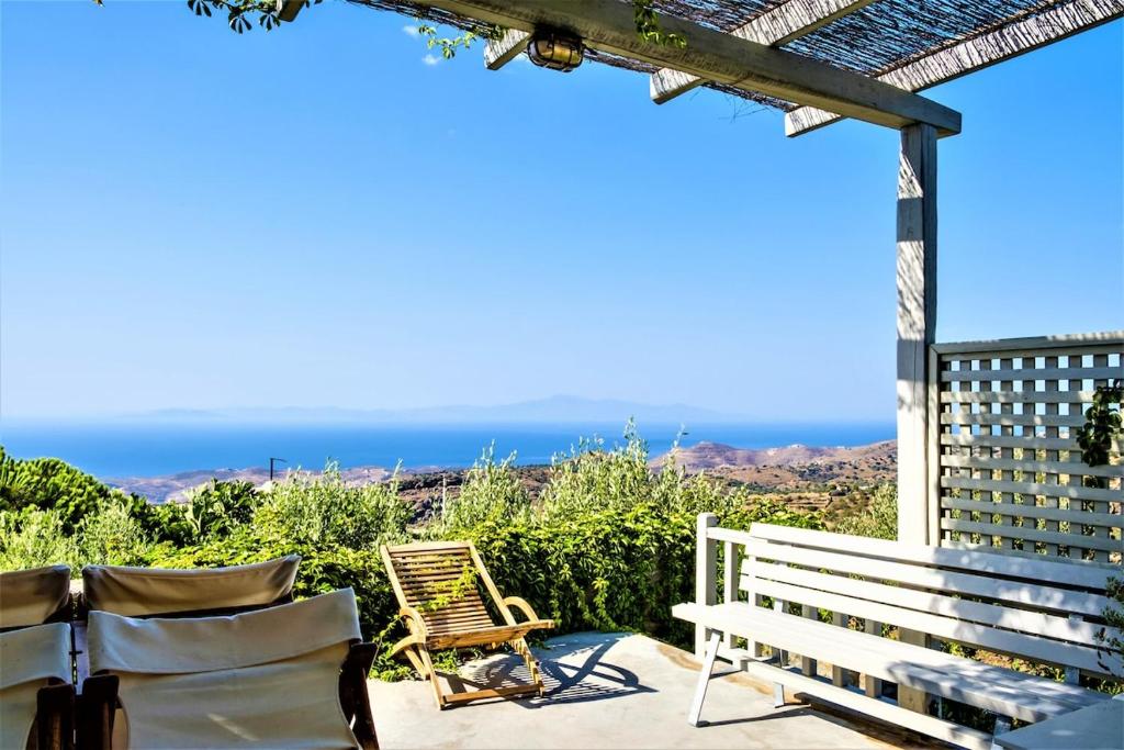 a patio with a bench and a view of the ocean at The Ioulis Pool in Ioulis