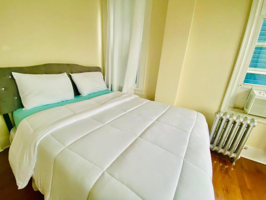 a white bed in a room with two windows at CaneView Properties - 1 in Irvington