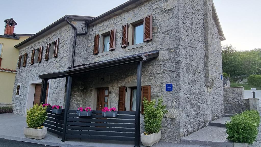 a stone building with potted plants on the front at Villa Kos1 in Erkovčići