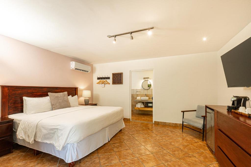 ein Schlafzimmer mit Bett, Schreibtisch und Fernseher in der Unterkunft Boutique Surf Hotel Rip Jack Inn in Playa Grande