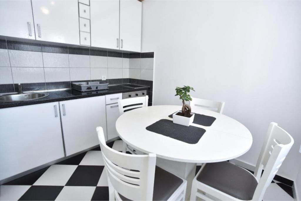 a white kitchen with a white table and chairs at Apartman Lavanda in Sutomore