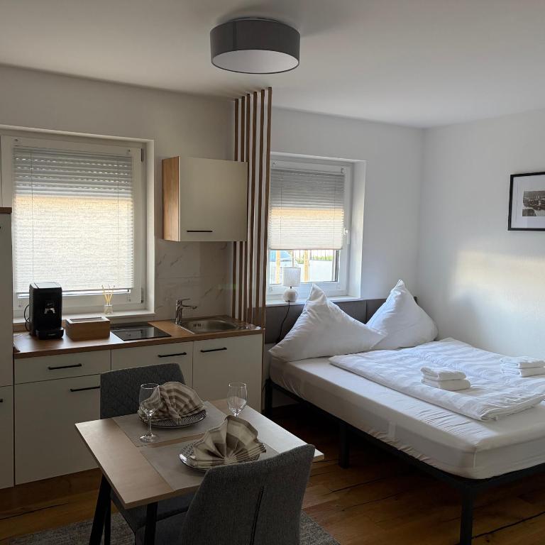 a room with a bed and a table and a kitchen at Ferienwohnung Mia in Büchlberg