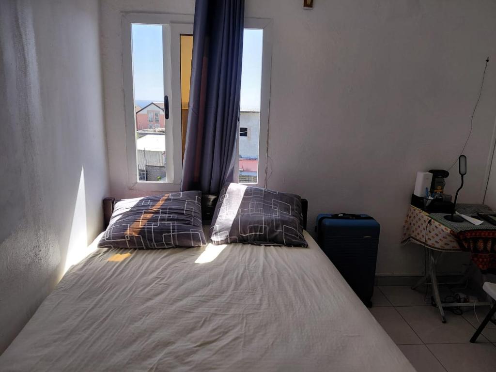 a bed with two pillows in a room with a window at Résidence Al-amine in Koungou