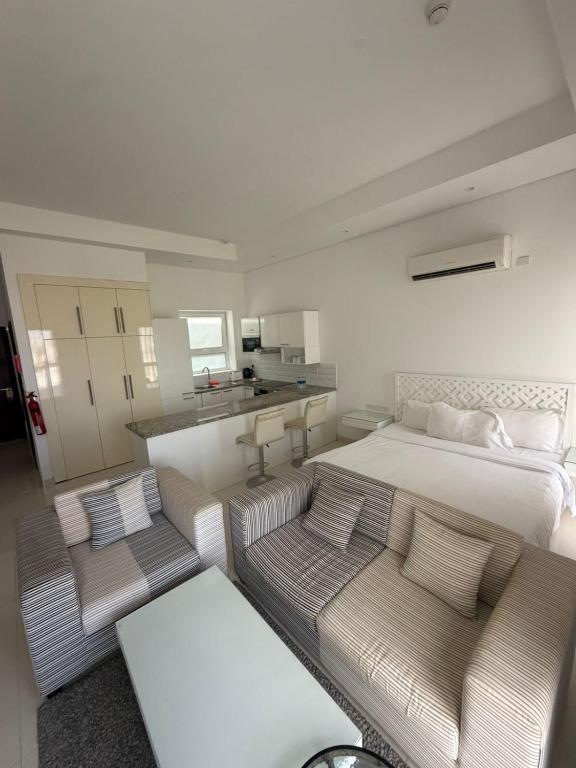 a bedroom with a bed and two couches and a kitchen at Hawana Studio in Salalah