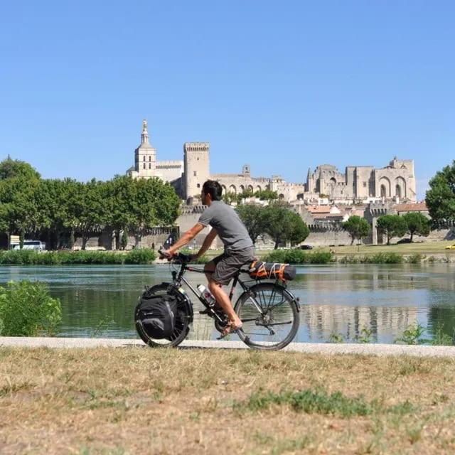 a man riding a bike next to a body of water at Au 3 bis in Caderousse