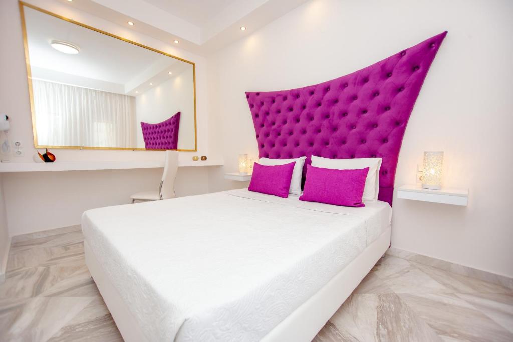 a bedroom with a large white bed with purple headboard at Ilion Luxury Studios & Apartments in Asprovalta