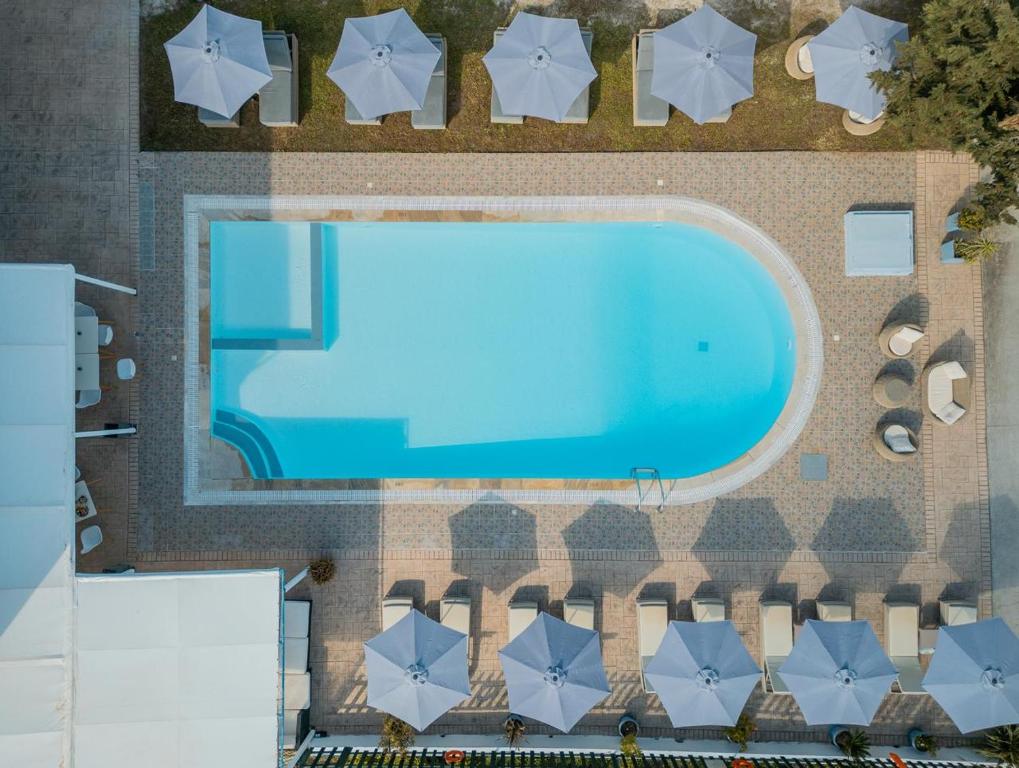 Draufsicht auf ein Schwimmbecken mit Sonnenschirmen in der Unterkunft Melitsa Corfu Hotel in Sidari